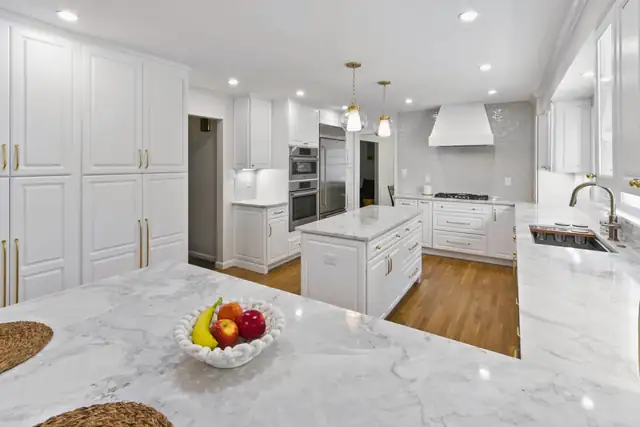 White kitchen remodel in Bethesda, MD with marble island, brass hardware and hardwood floors