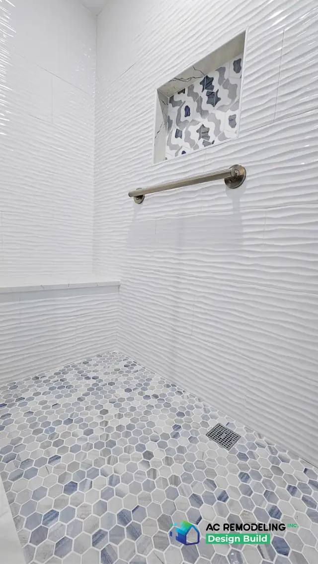 Rockville, MD shower with wave-texture white tile, quartz bench, grab bar and blue hex mosaic floor